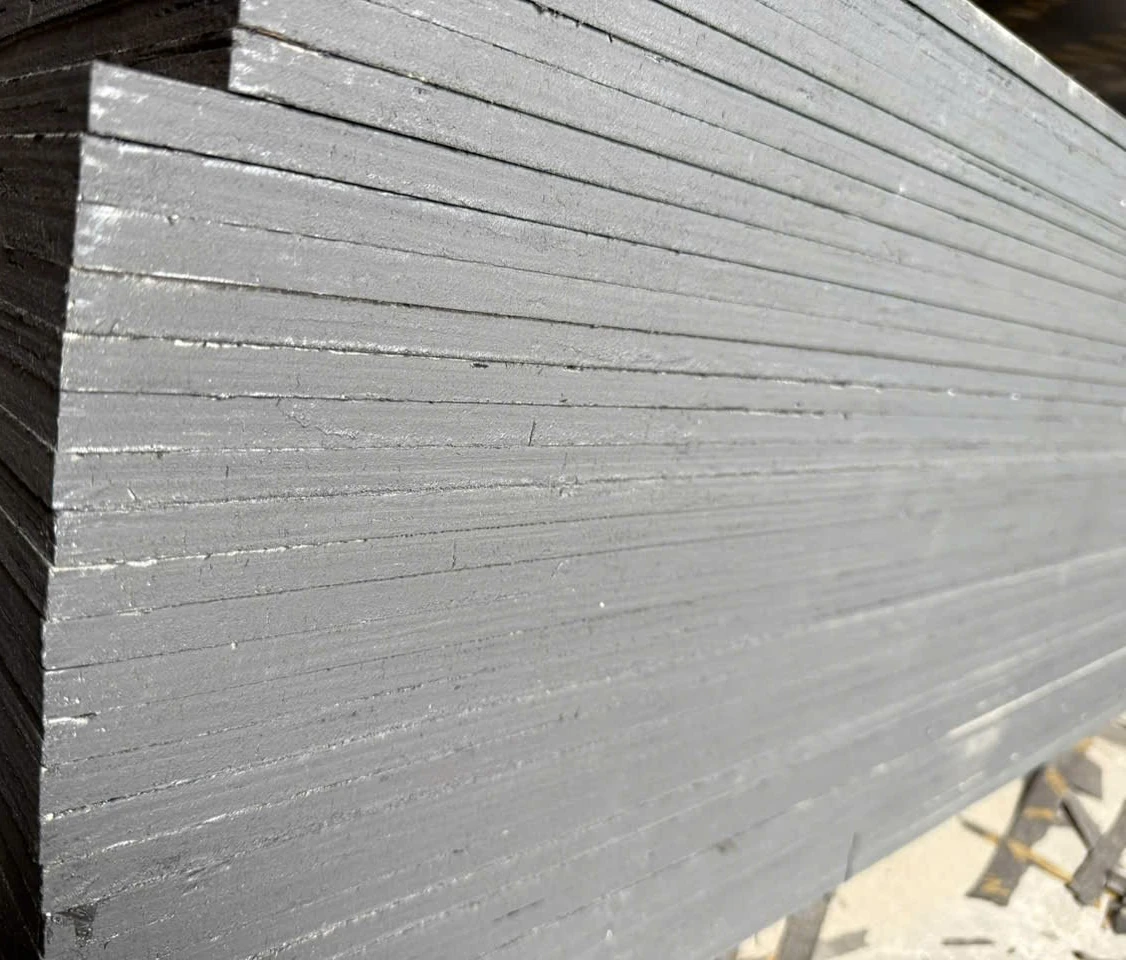 Dark sealed edges of a film-faced plywood stack, sheets stepping back in perspective