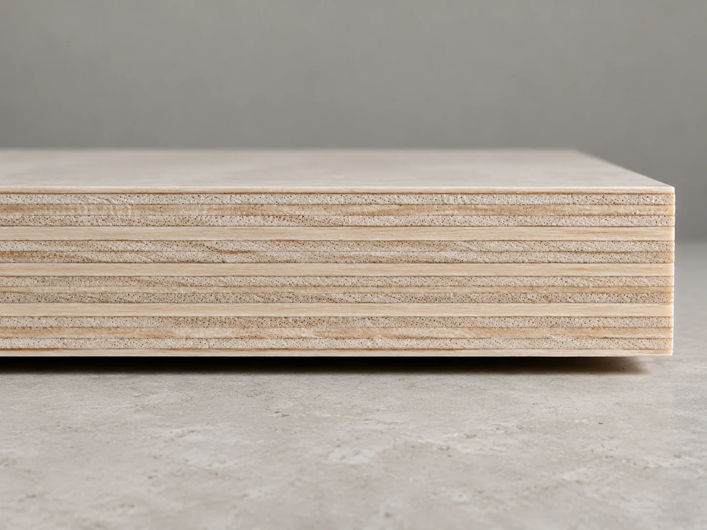 Sawn edge of a white Styrax-core plywood panel showing thin cross-laid veneer layers and fine glue lines